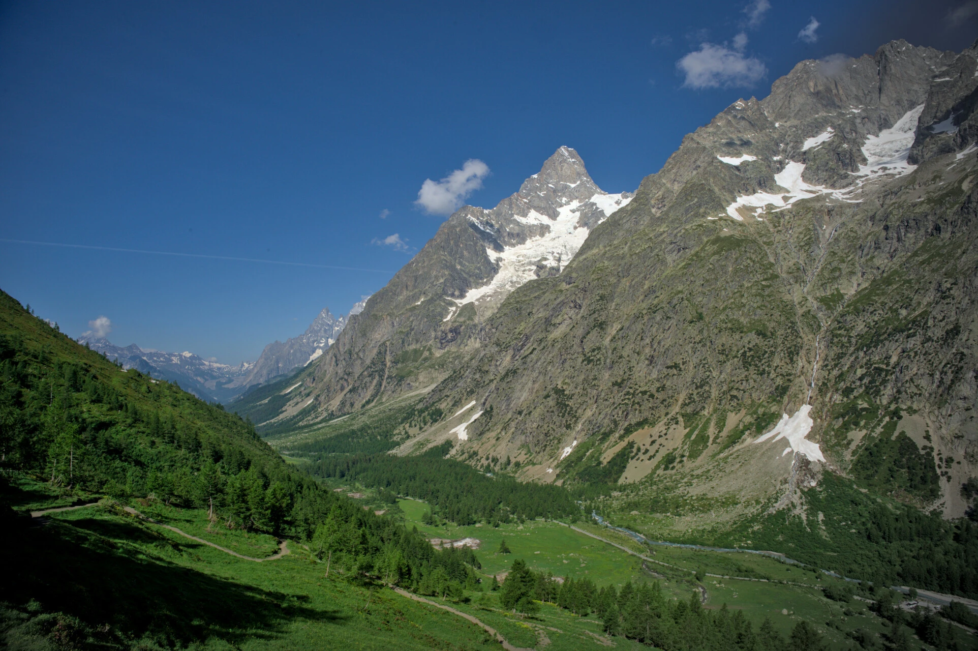 Alpweiden im italienischen Val Ferret am Morgen, zwischen Lärchen und schneebedeckten Gipfeln